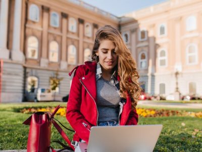 curious-female-student-gray-sweater-sitting-grass-with-computer_197531-6967