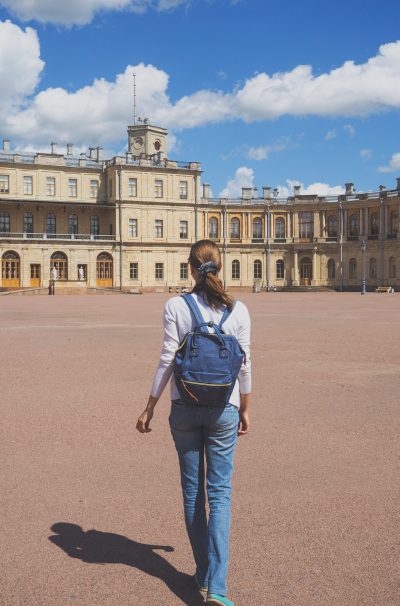 Tourist cute slender woman, seeing the sights. Happy woman traveling on the background of an ancient Palace.